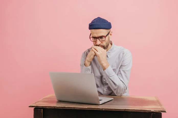 Man studying a laptop at a wooden table