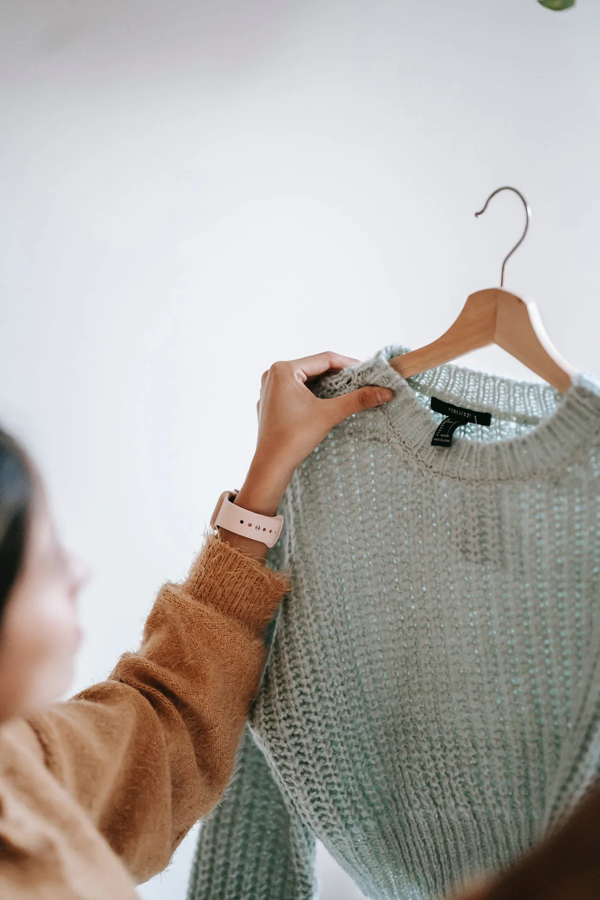 Person holding a sweater on a hanger.