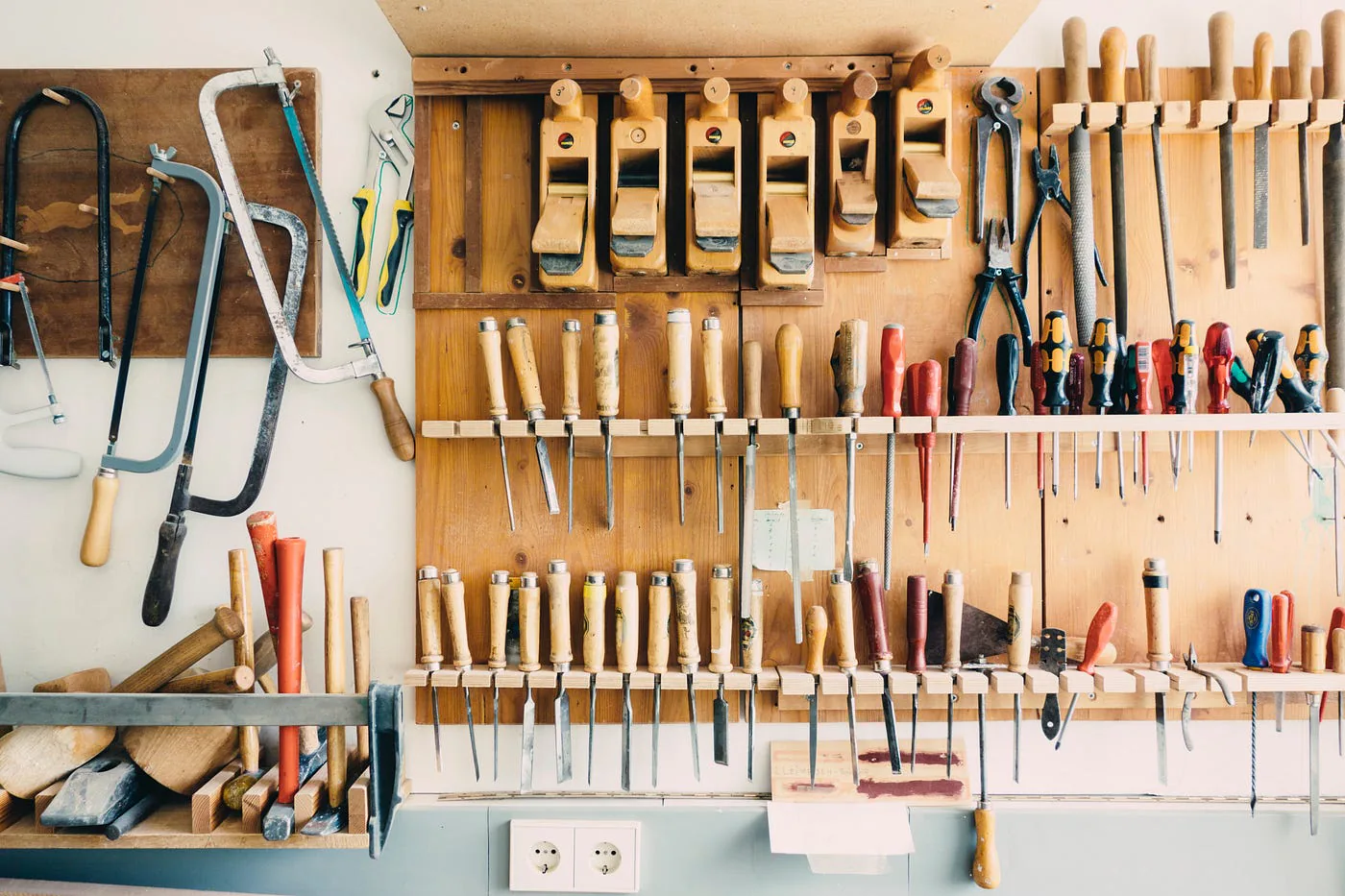Établi avec des outils de menuiserie rangés au mur.