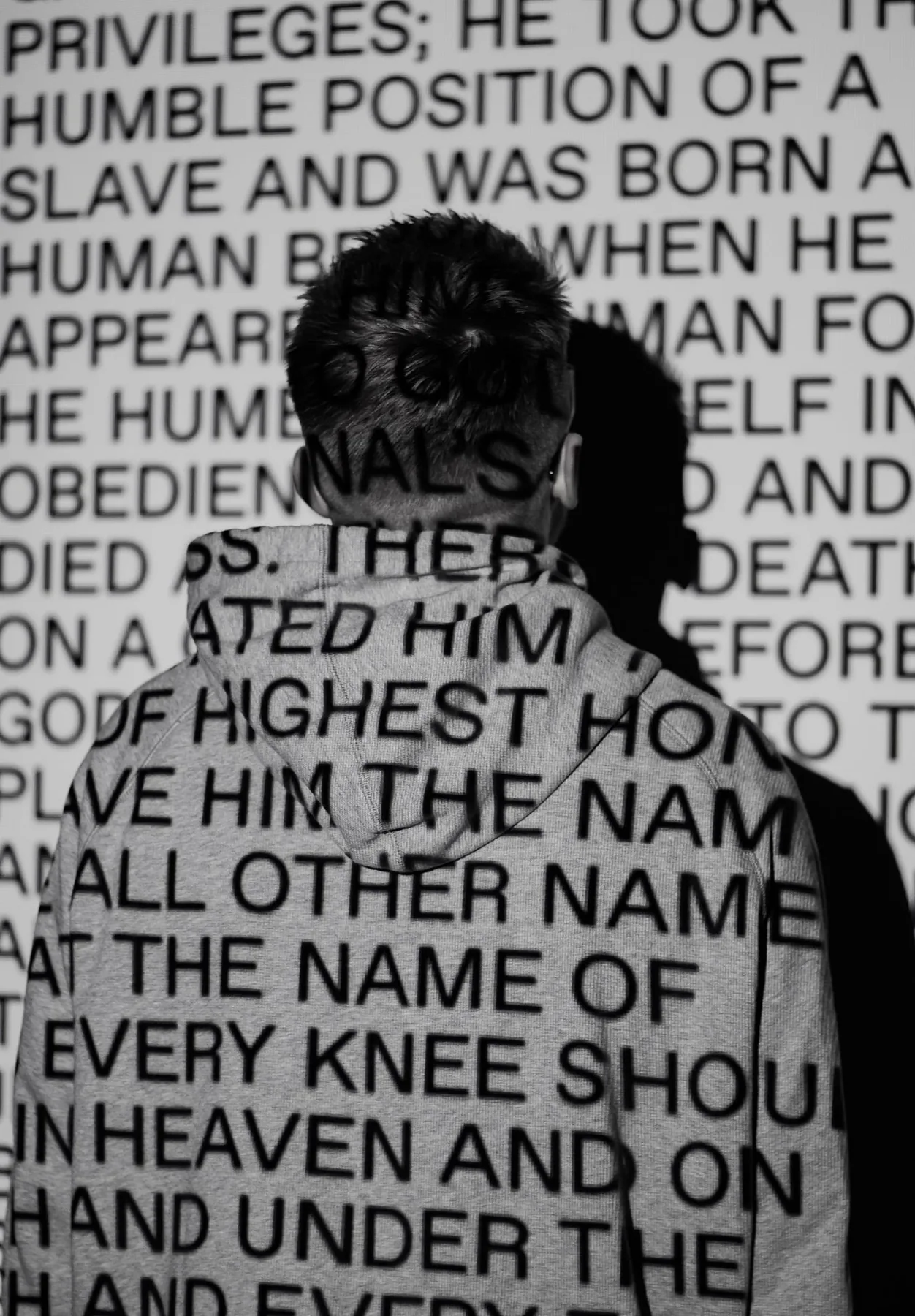 Une personne devant un mur couvert de mots.